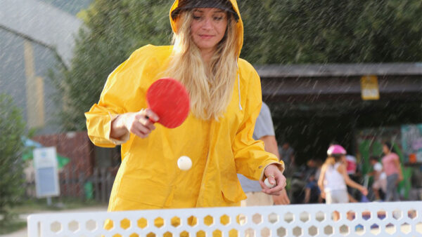 A woman playing table tennis on an outdoor table.